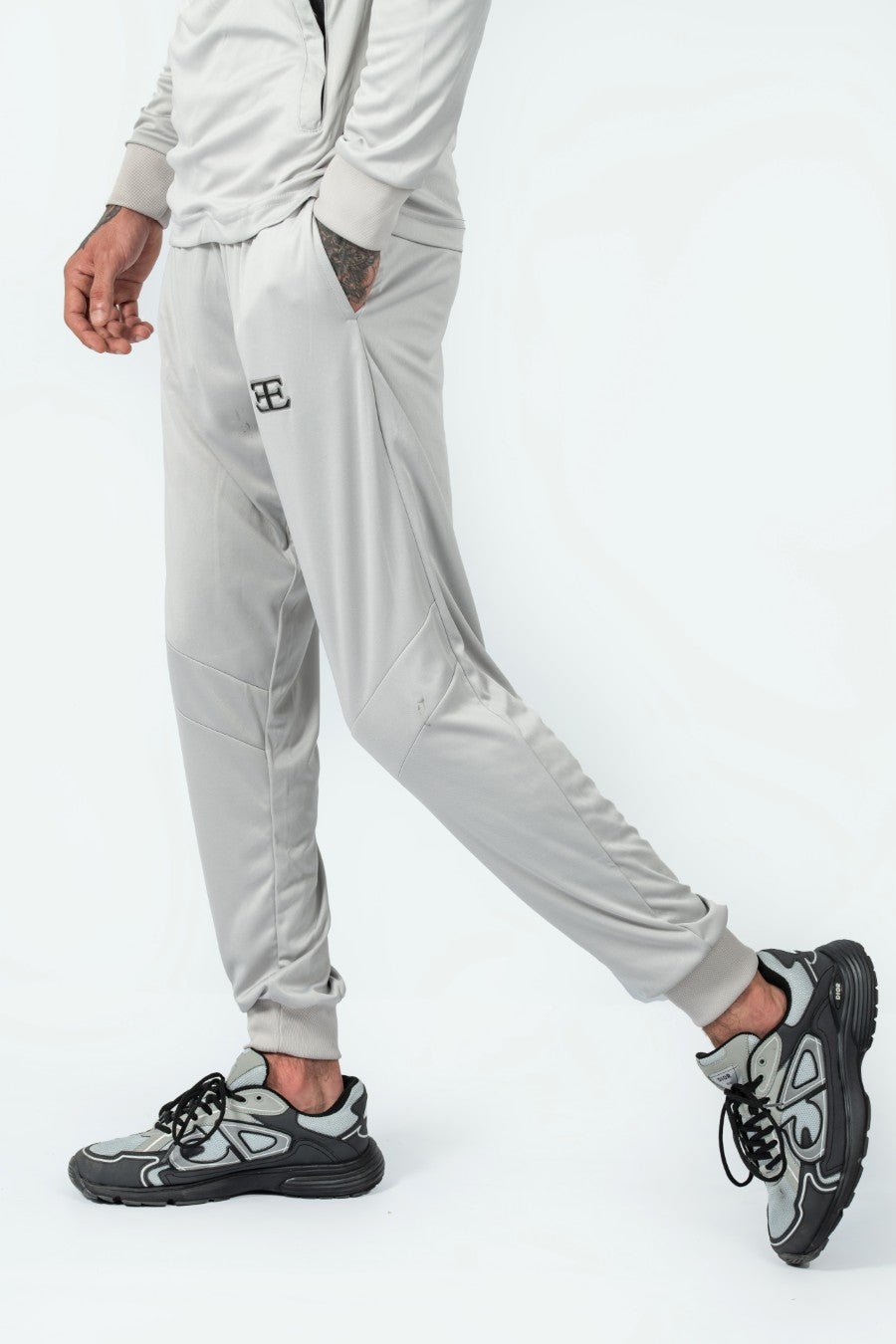 man wearing gray tracksuit pants with a logo on a white background