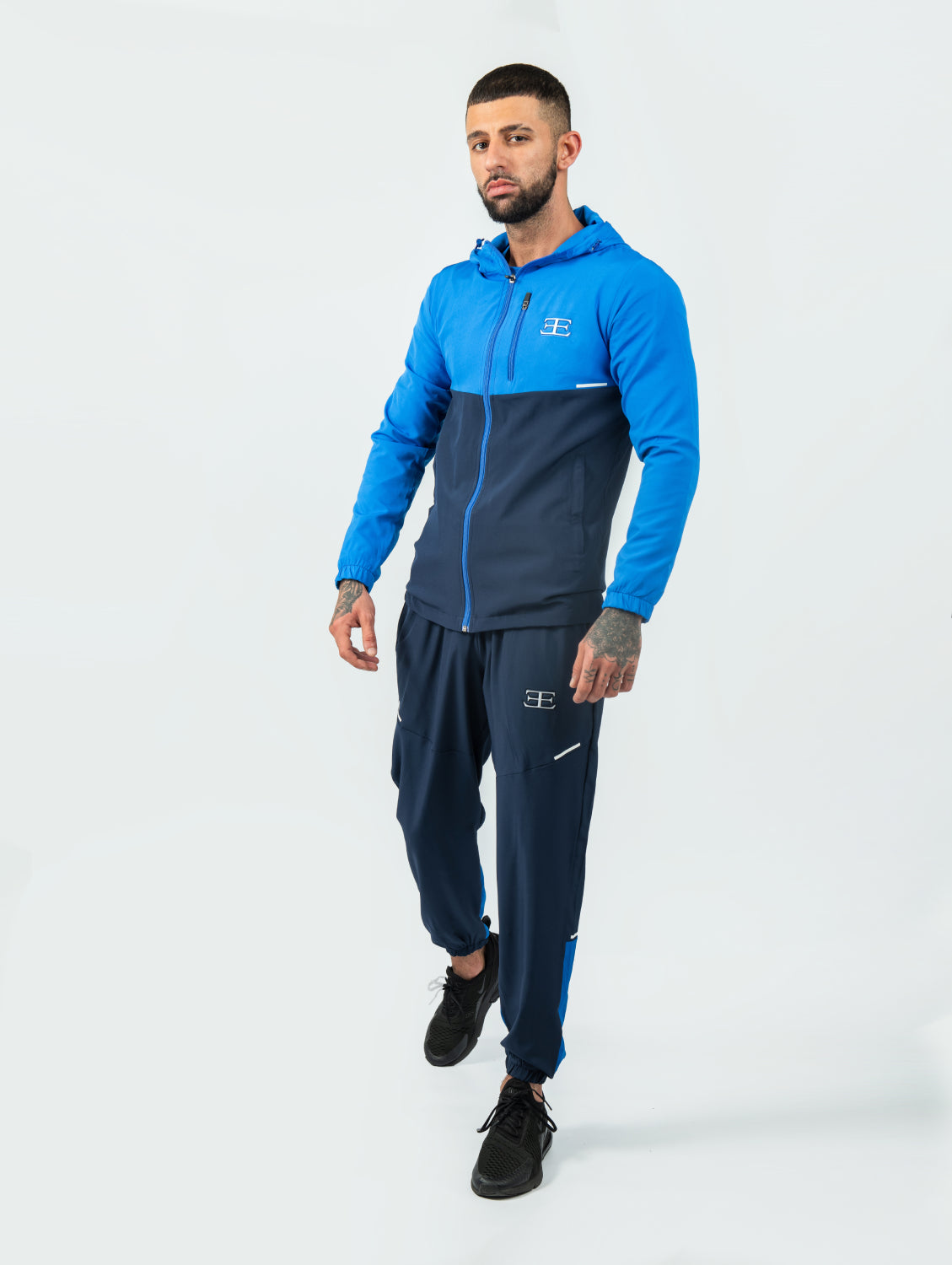 Man wearing a blue and navy tracksuit on a white background