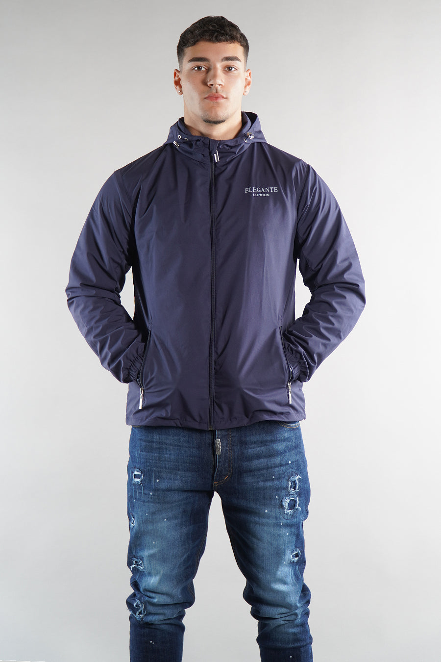 Man wearing a navy jacket with a brand logo on a white background