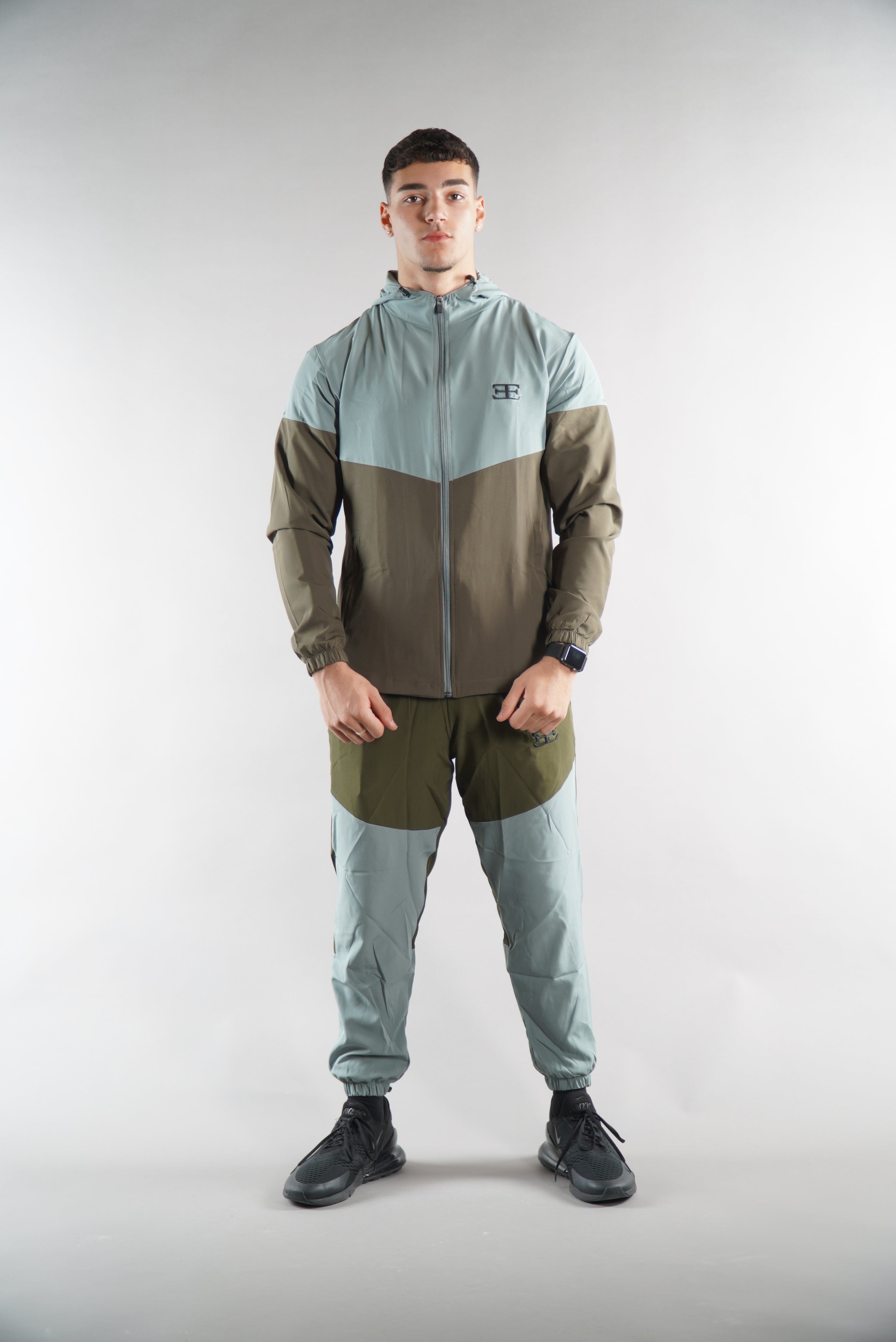 Man wearing Olive Green tracksuit Jacket and tracksuit pants set, sports clothing for men, white background