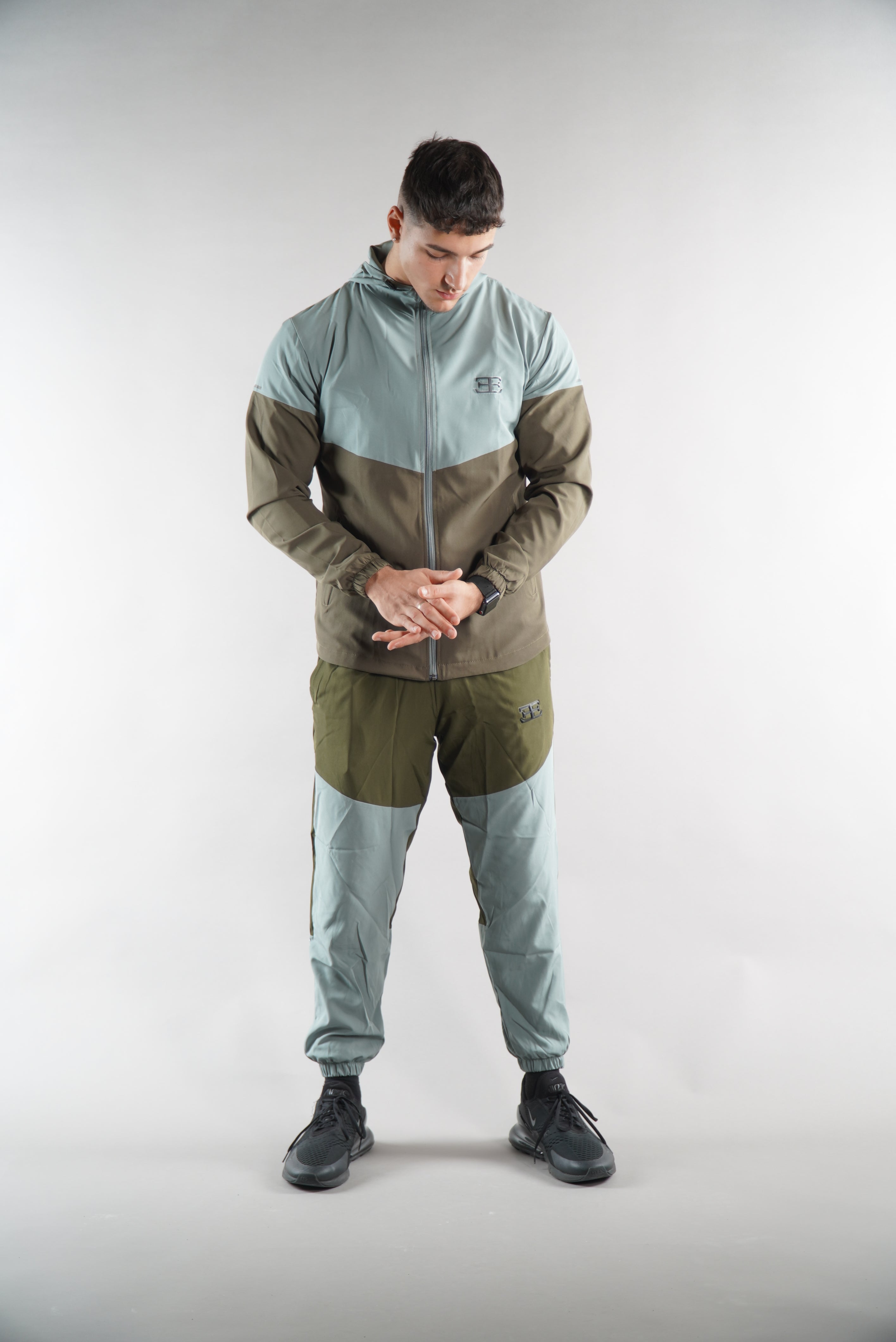 Man wearing Olive Green tracksuit Jacket and tracksuit pants set, sports clothing for men, white background