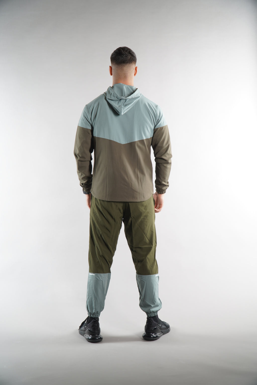 Man wearing Olive Green tracksuit Jacket with hood and tracksuit pants set, from the back view on white background, , sports clothing for men
