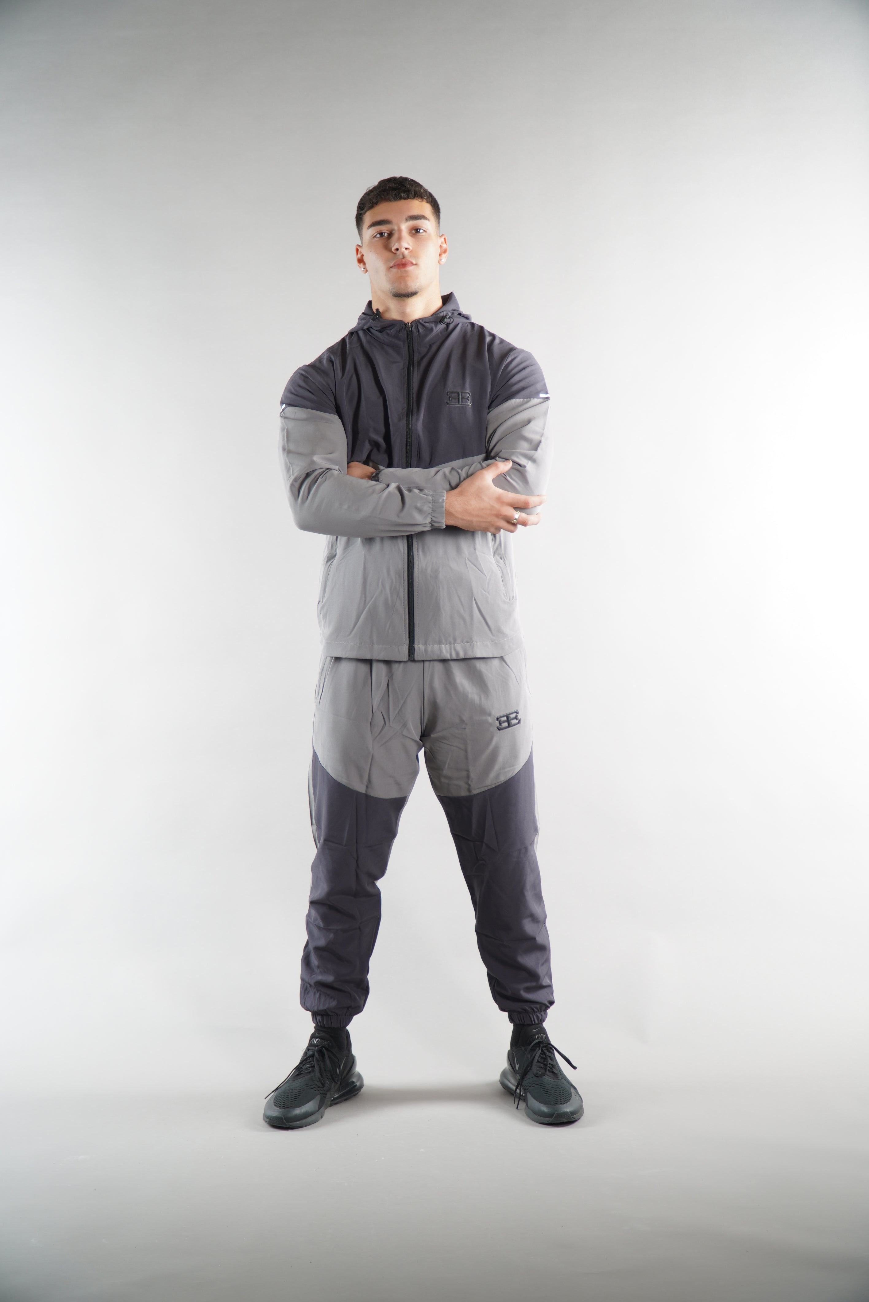 man wearing Grey Tracksuit joggers and tracksuit jacket with hood his arms folded, activewear clothing