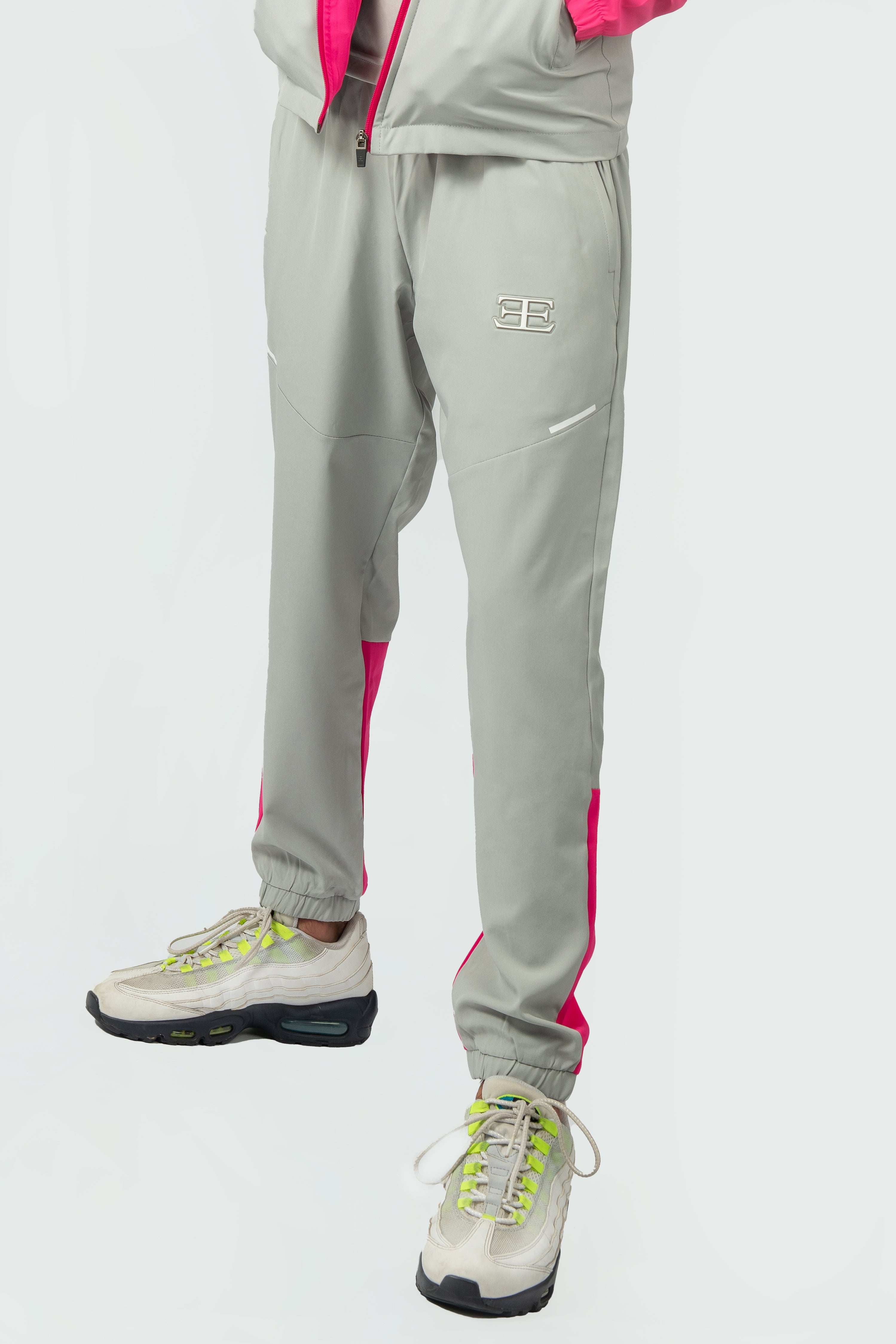 Gray tracksuit with pink accents and white sneakers on a light gray background