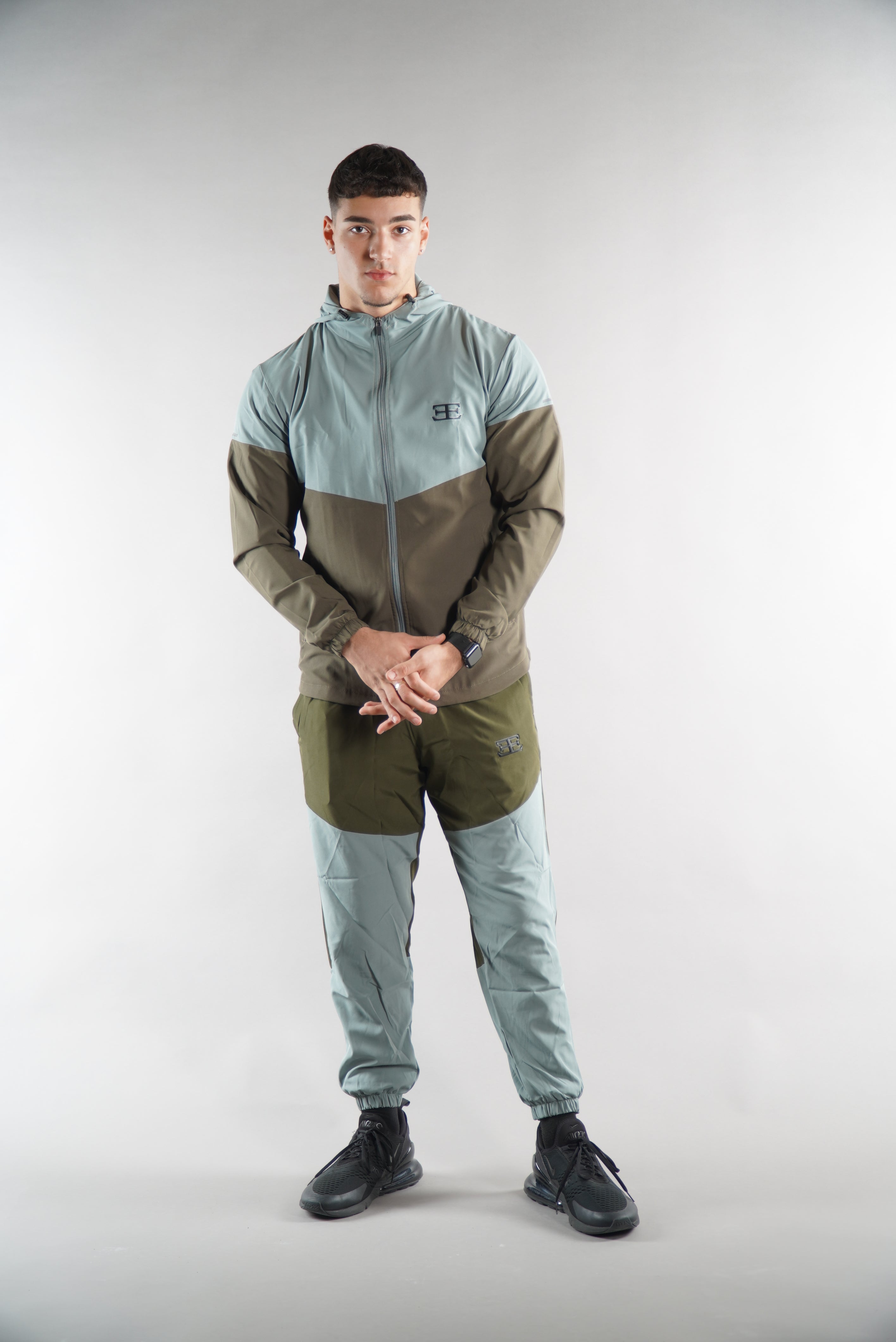 Man wearing Olive Green tracksuit Jacket with hood and tracksuit pants set, from the back view on white background, , sports clothing for men