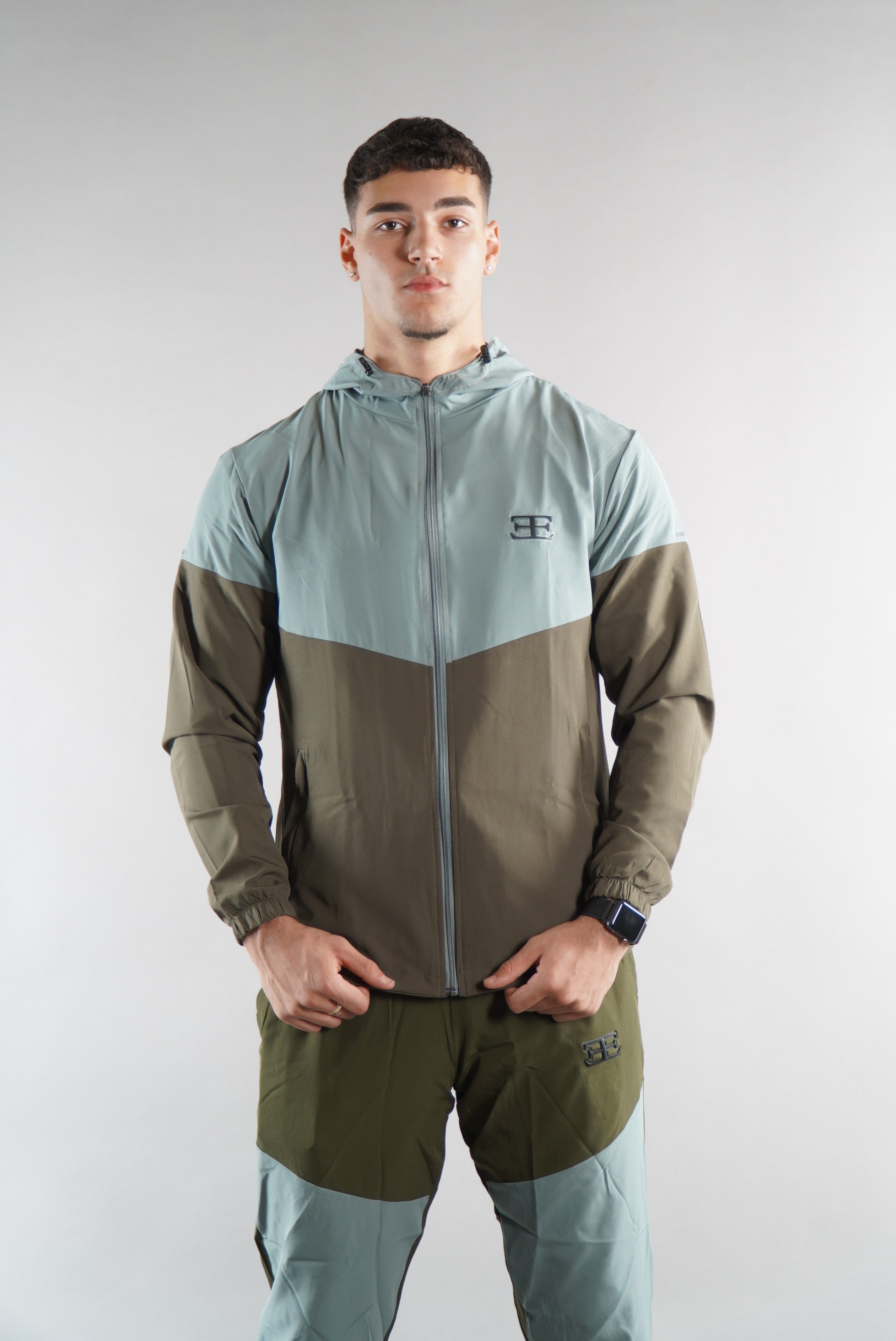 Man wearing Olive Green tracksuit Jacket with hood and tracksuit pants set, from the back view on white background, , sports clothing for men