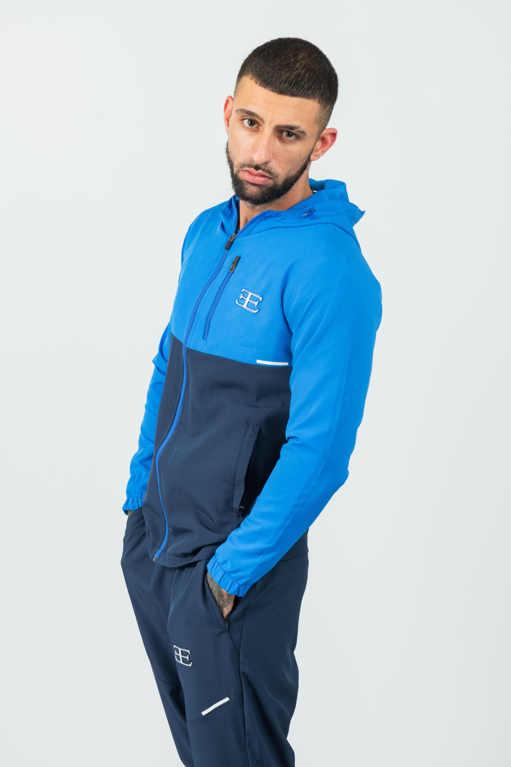 Man wearing a blue and navy tracksuit with elegante logo on a white background