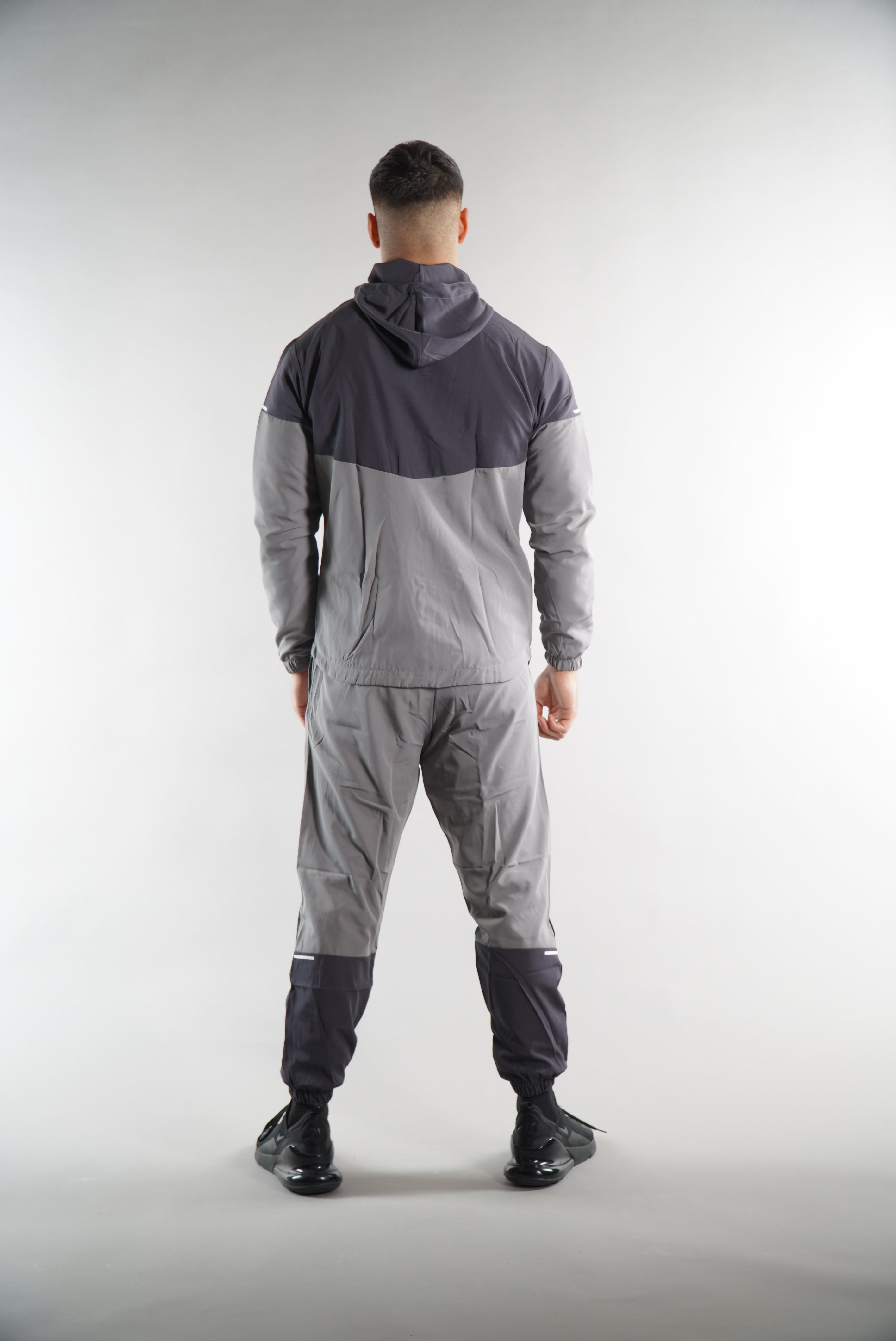 man wearing Grey Tracksuit joggers and tracksuit jacket with hood view from the. back, activewear clothing