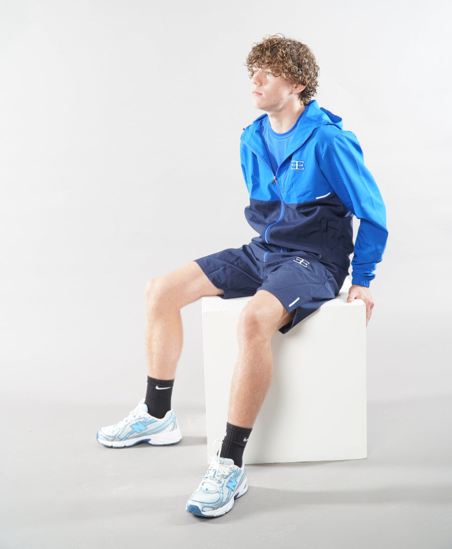 Man wearing Elegante Navy Blue Gym Shorts and tracksuit jacket, sat down