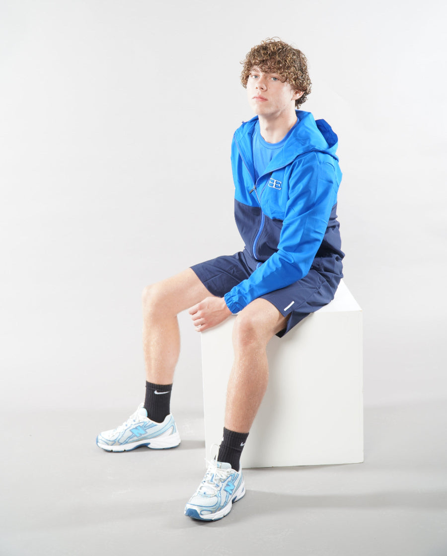 Man wearing Elegante Navy Blue Gym Shorts and tracksuit jacket, sat down