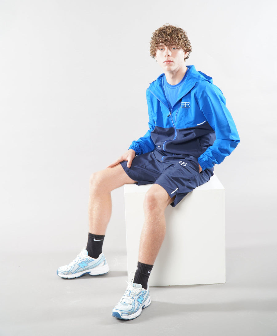 Man wearing Elegante Navy Blue Gym Shorts and tracksuit jacket, sat down