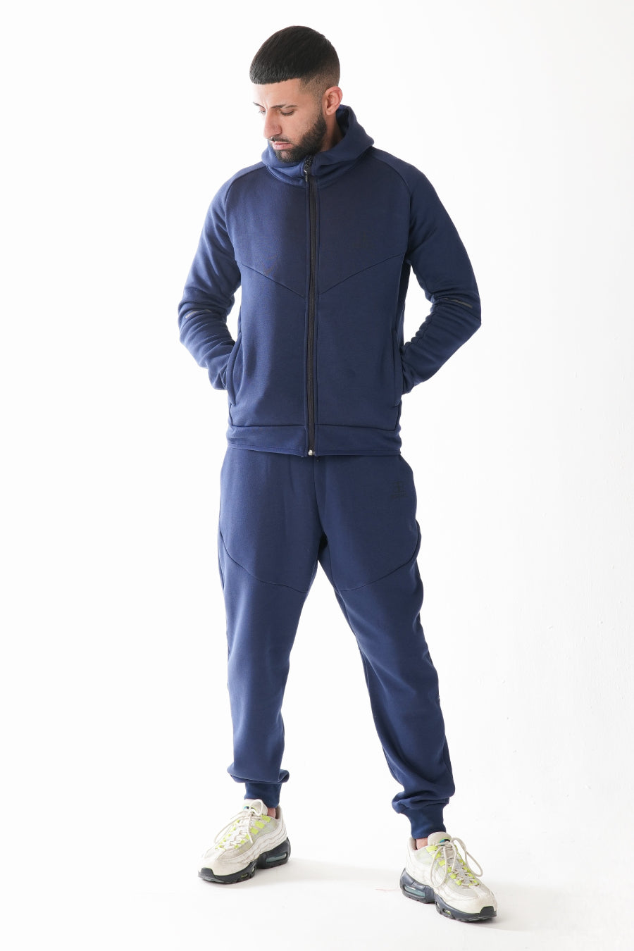 Man wearing a navy blue tracksuit on a white background