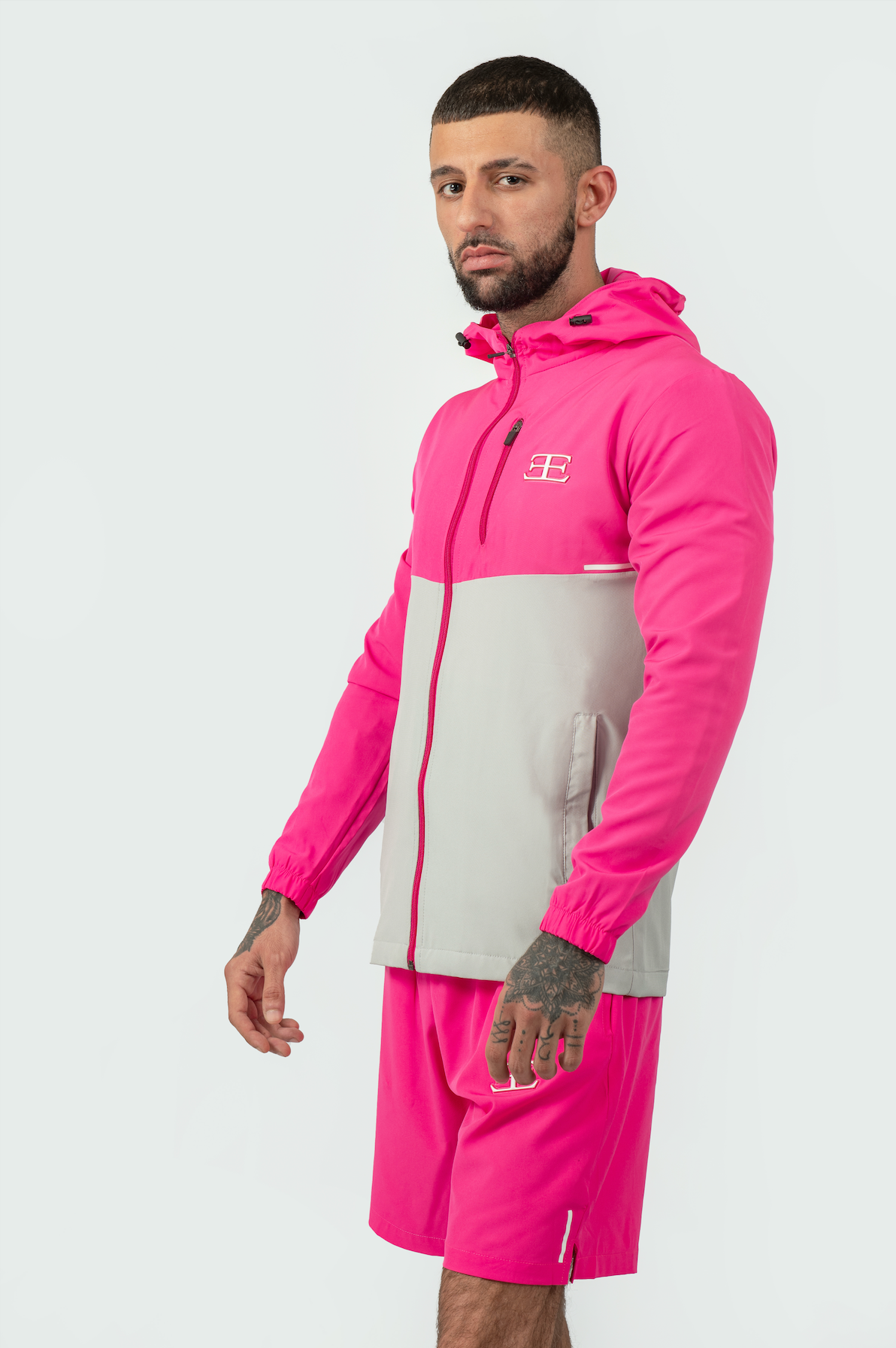 Man wearing a pink and gray tracksuit with a brand logo on a white background