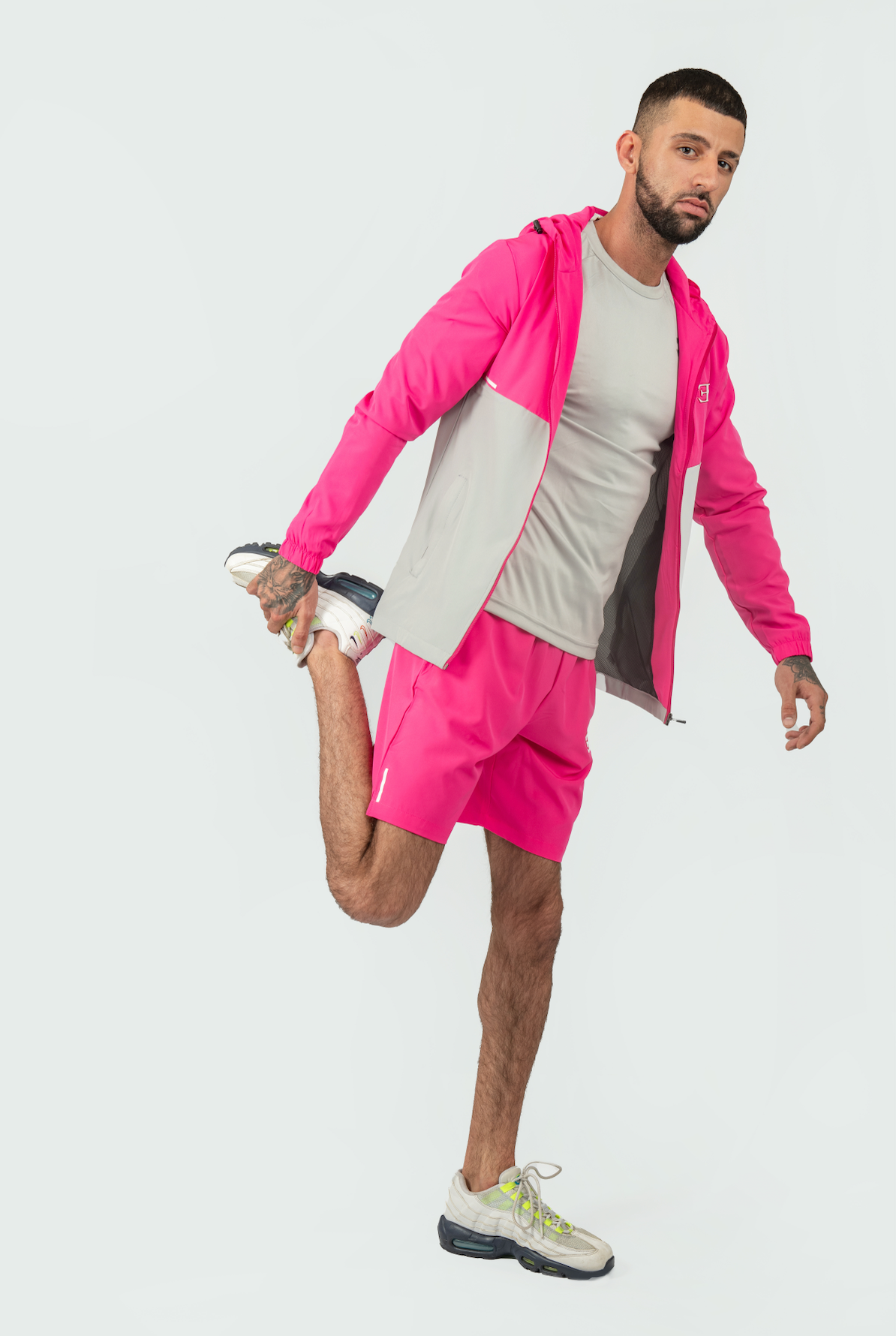 Man in pink athletic outfit stretching on a white background