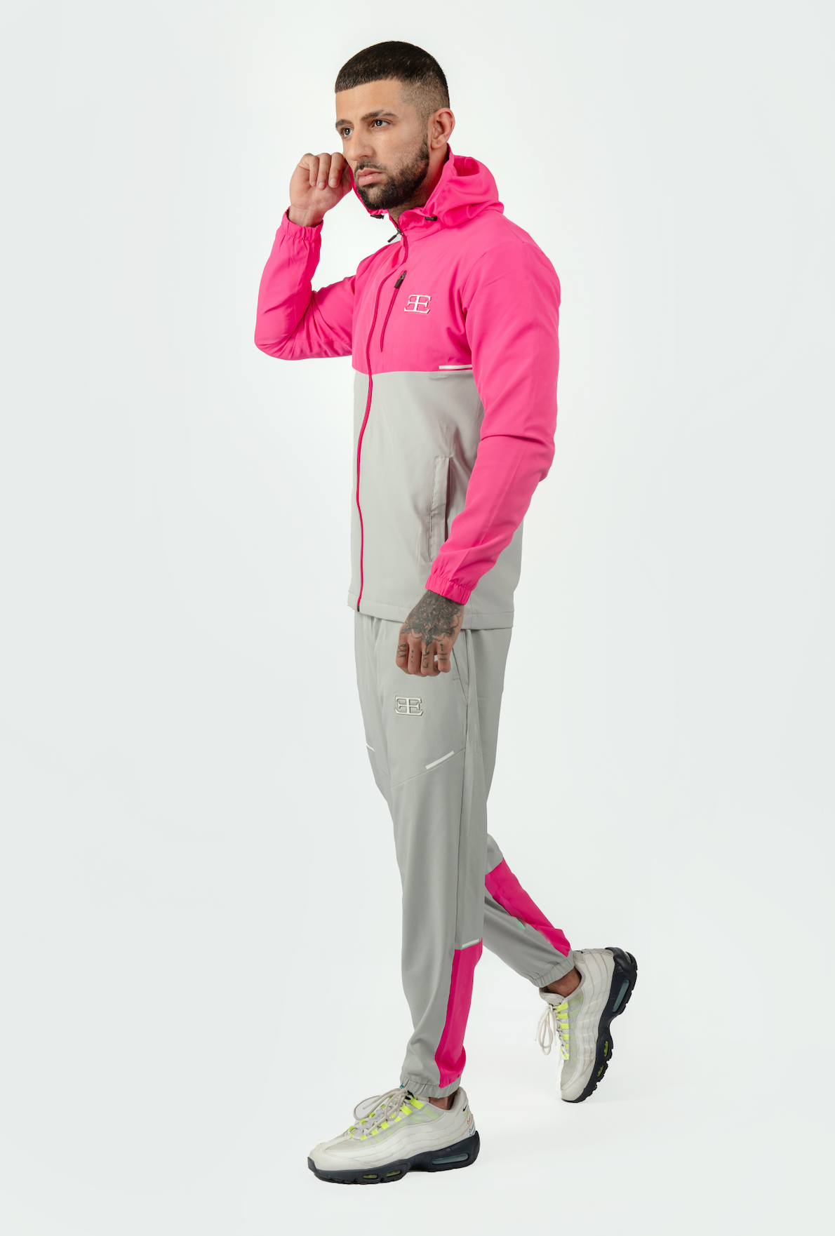 Man wearing a pink and gray tracksuit on a white background