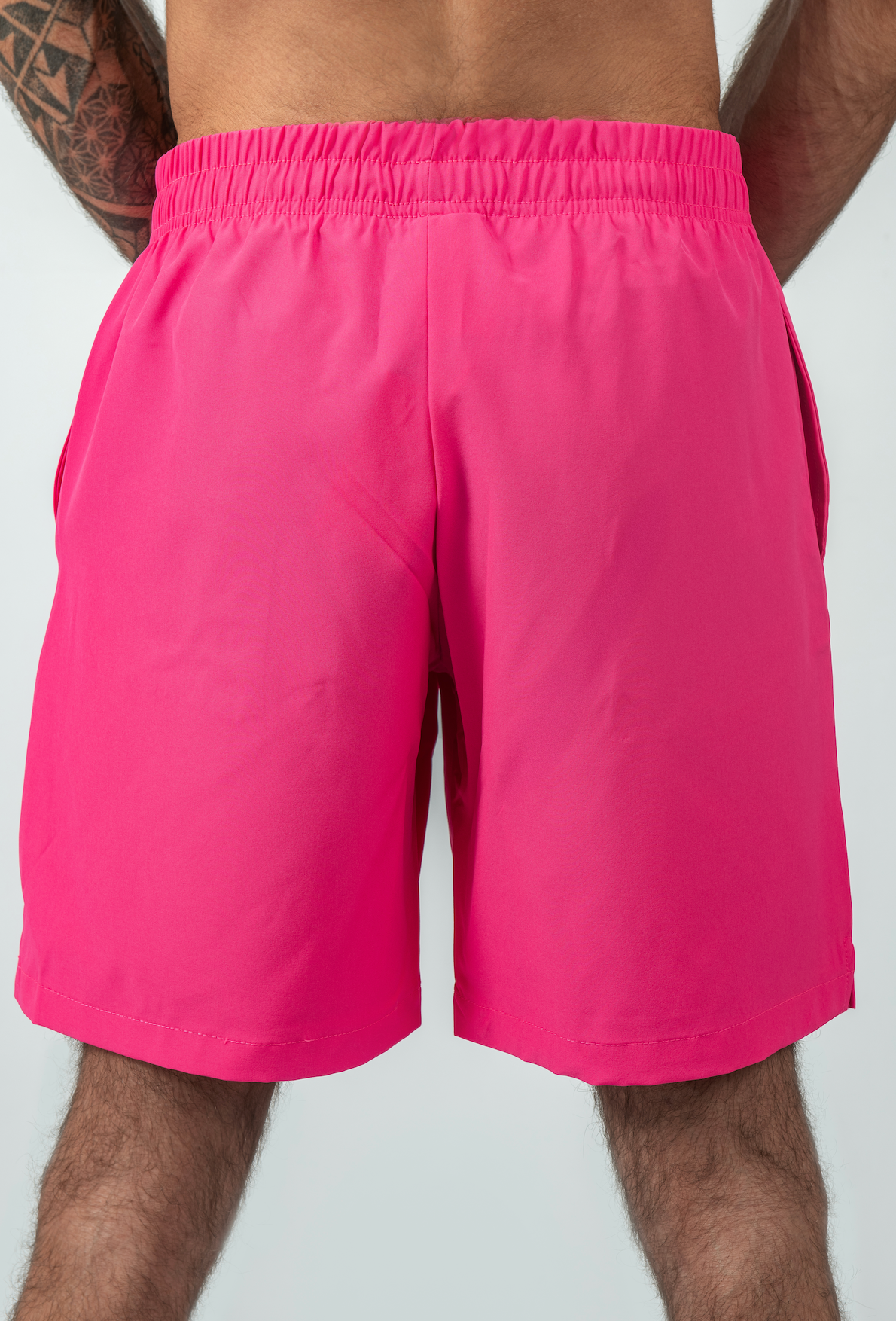 Person wearing bright pink shorts on a plain background