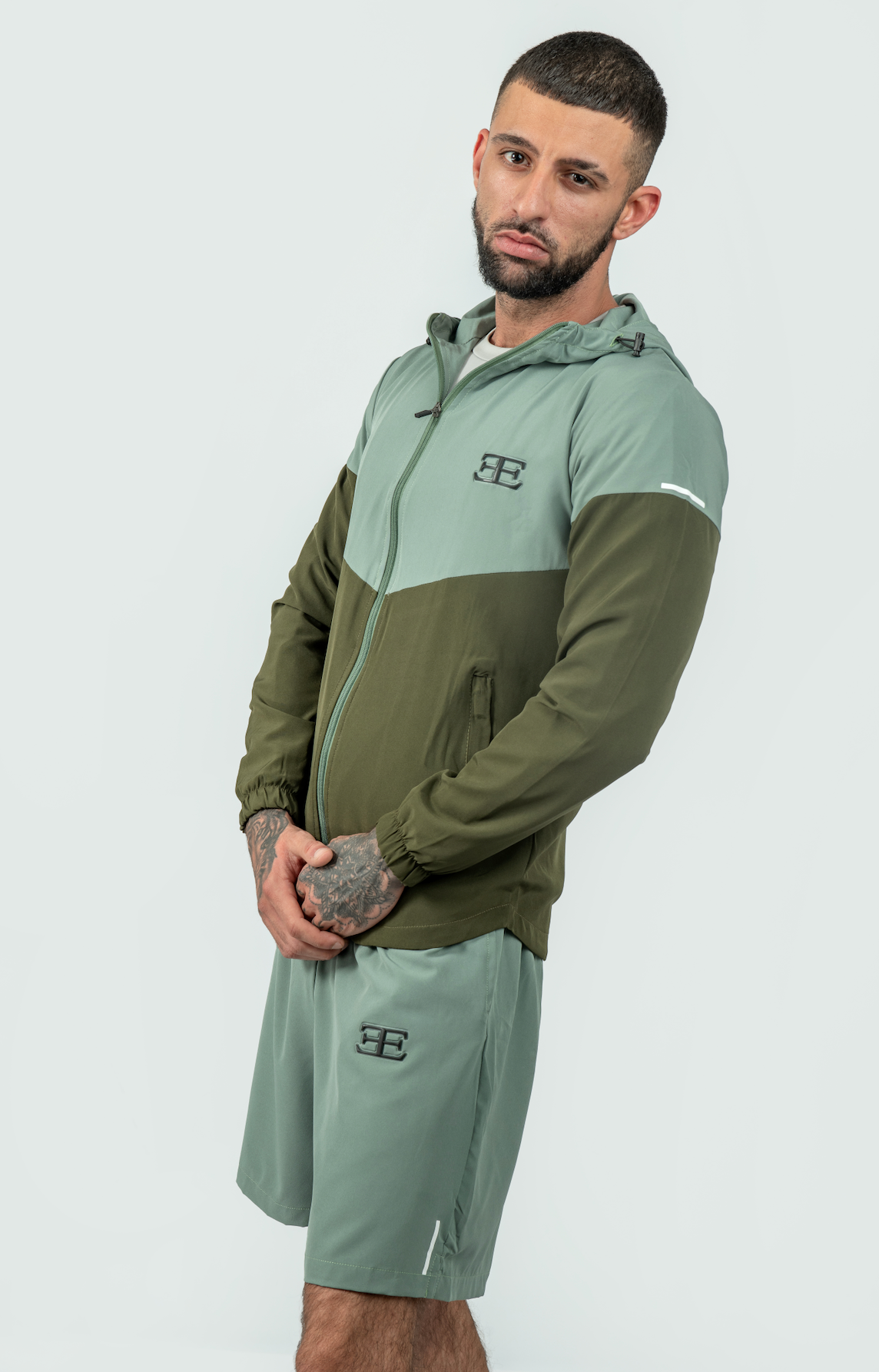 Man wearing a green and olive tracksuit on a white background
