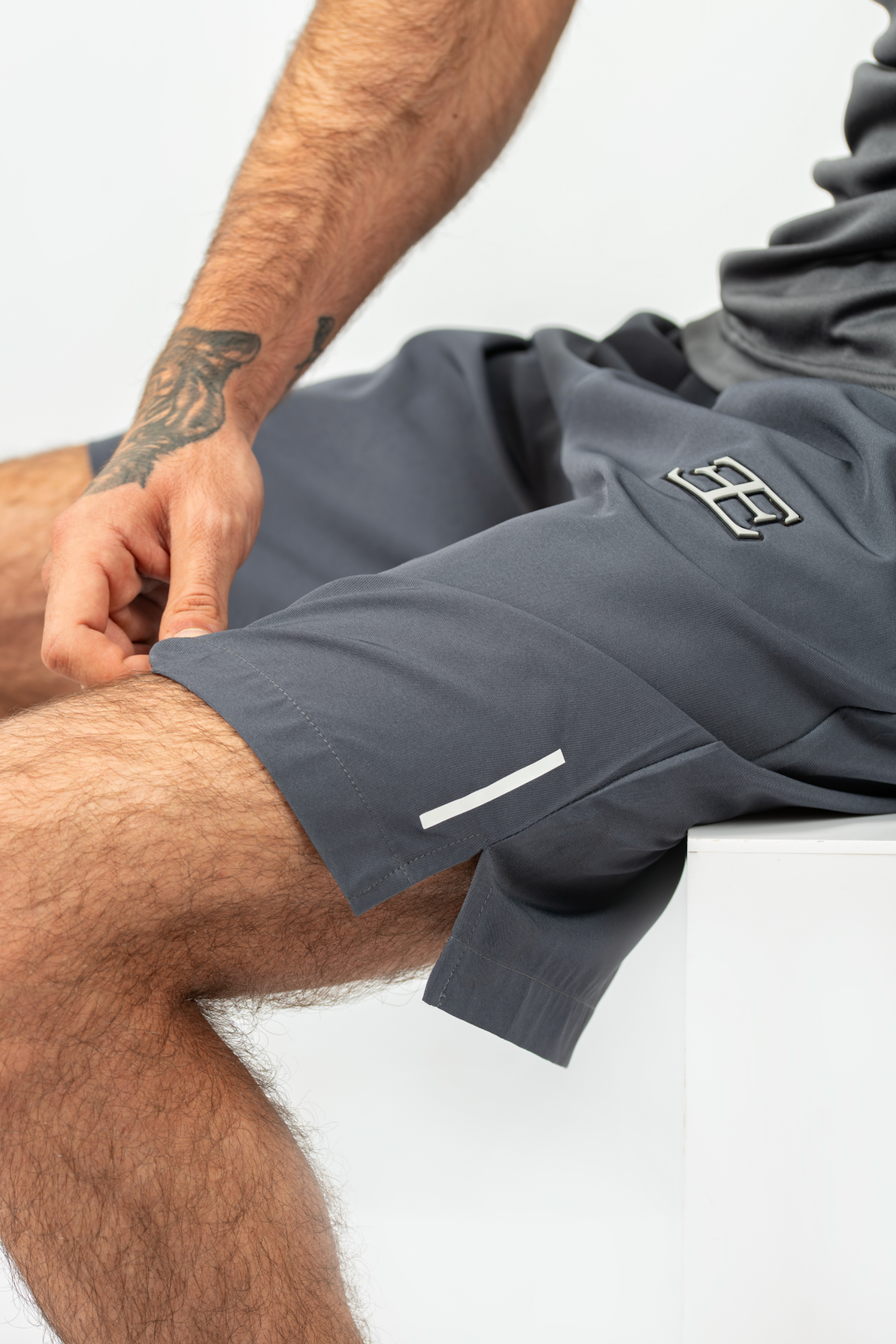 Person wearing gray athletic shorts with a brand logo on a white background
