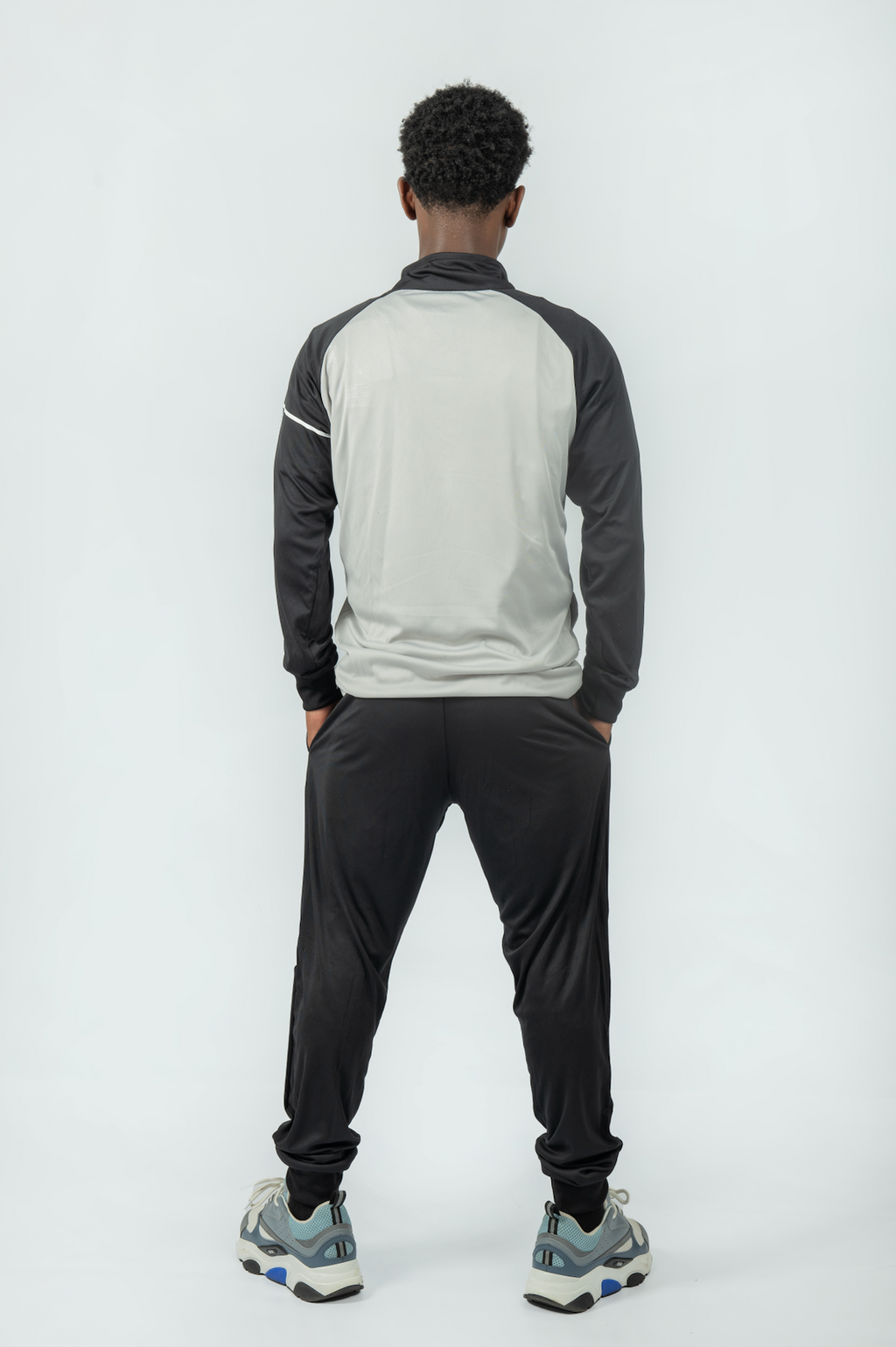 man wearing a gray and black tracksuit on a white background