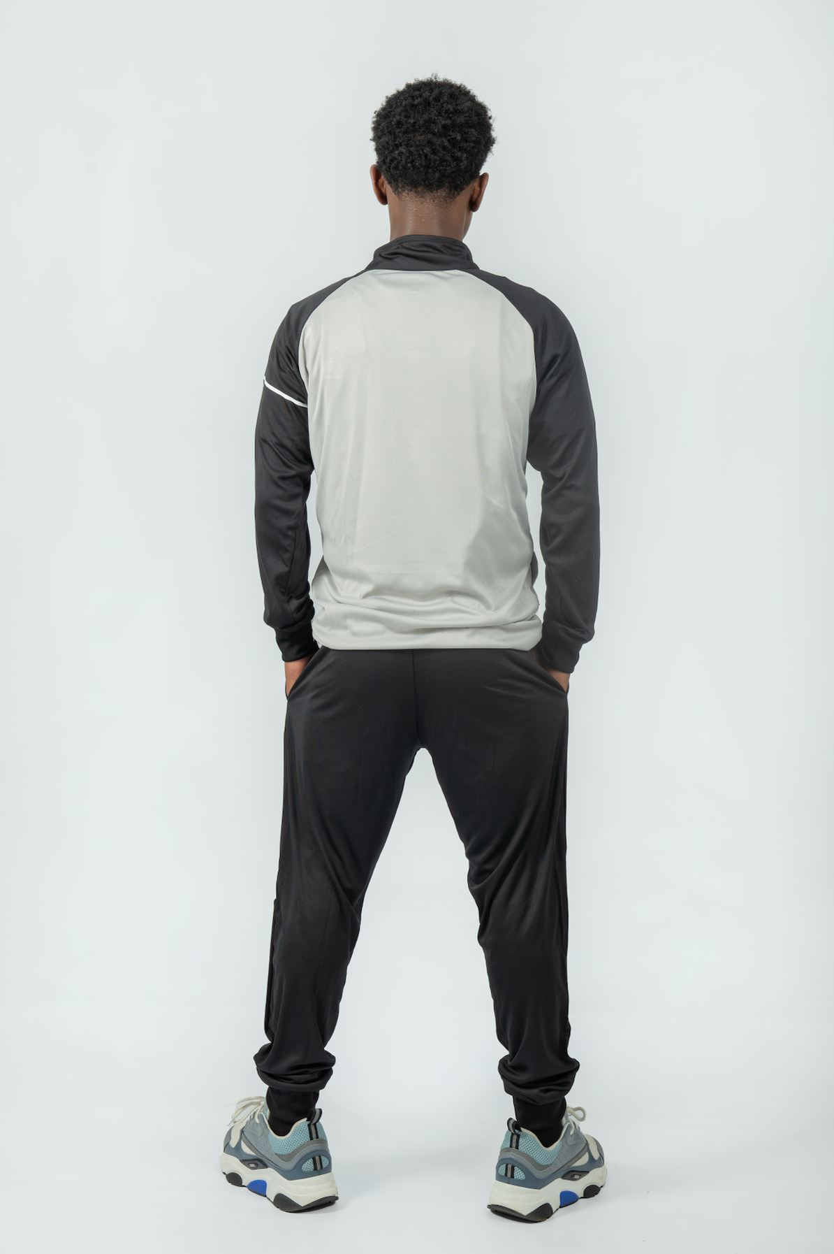 man wearing a gray and black tracksuit on a white background
