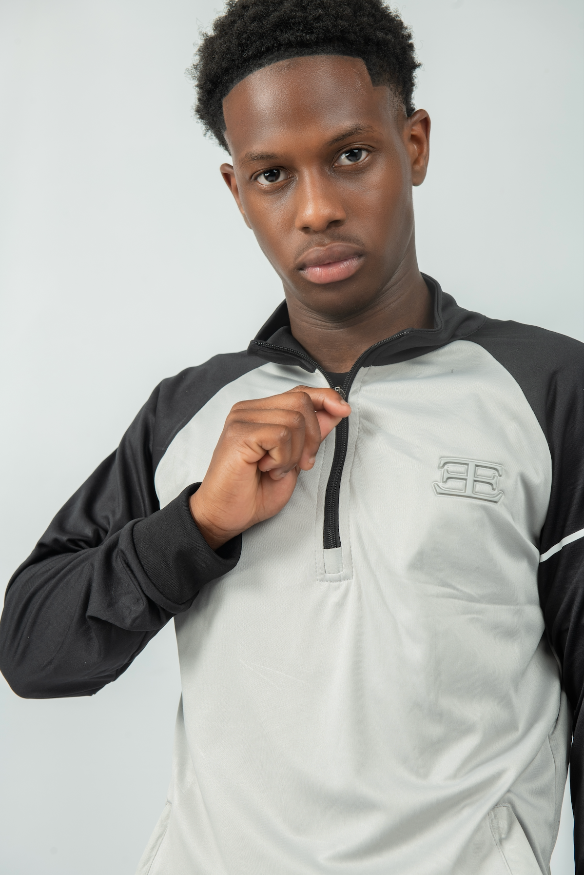 man wearing a black and gray jacket with a brand logo on a white background