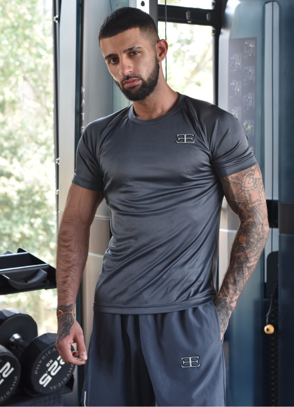 Man wearing a gray athletic outfit with a logo in a gym setting