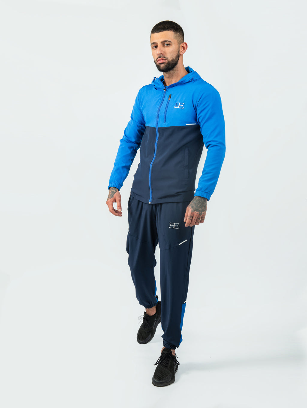 Man wearing a blue and navy tracksuit on a white background
