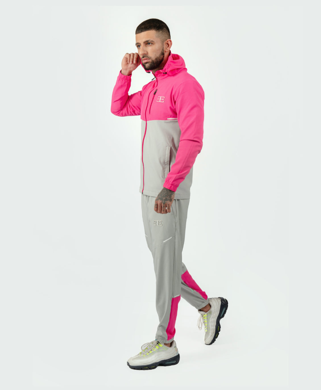 man in pink and grey tracksuit jacket and joggers with white background