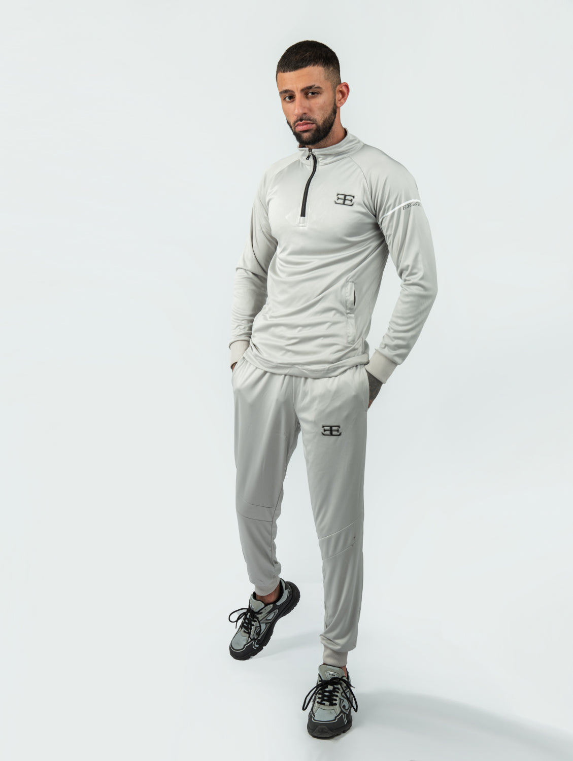 Man wearing a gray tracksuit with elegante logo on a white background
