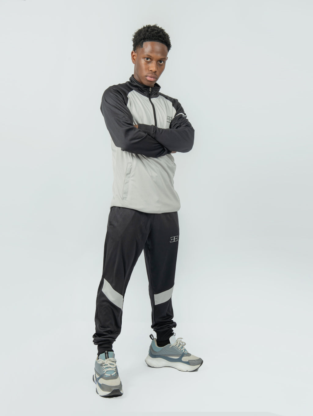 man wearing a gray and black tracksuit with a brand logo on a white background