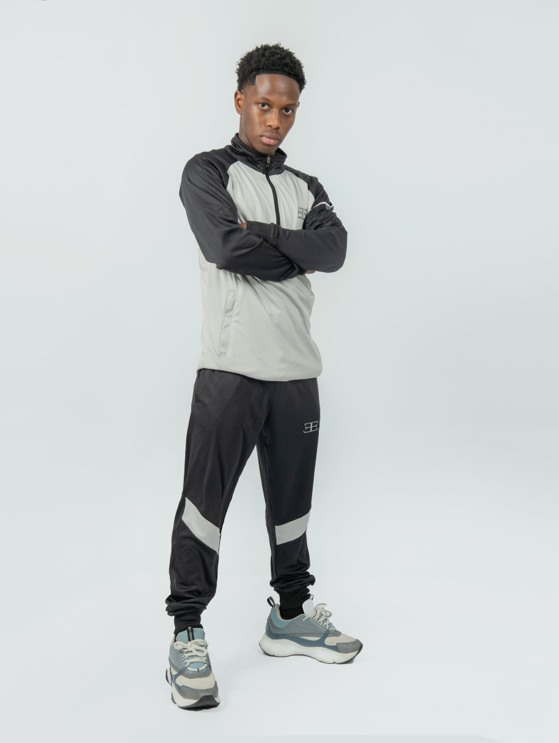 man wearing a gray and black tracksuit with a brand logo on a white background