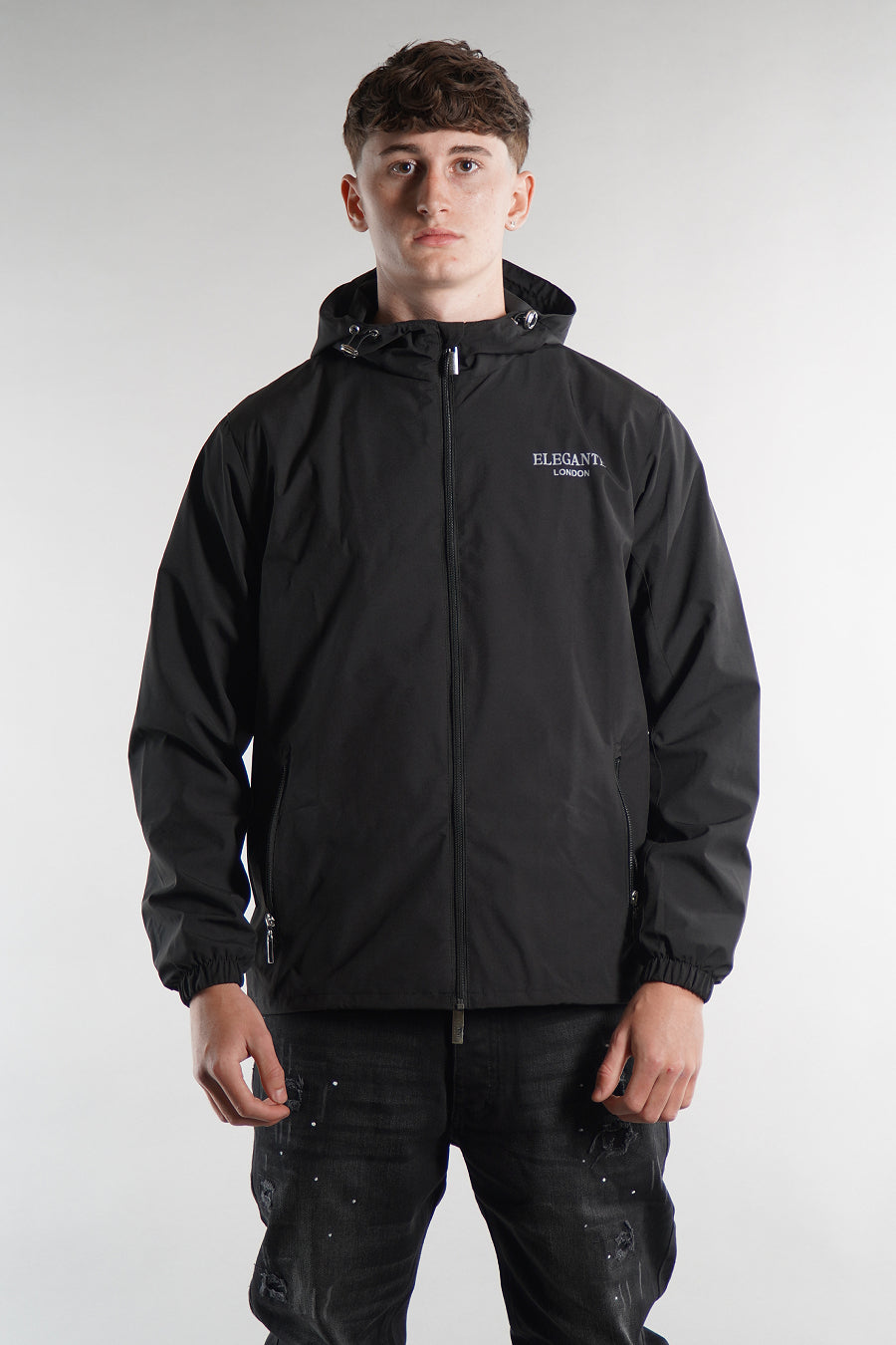 man wearing a black jacket with a brand logo on a white background