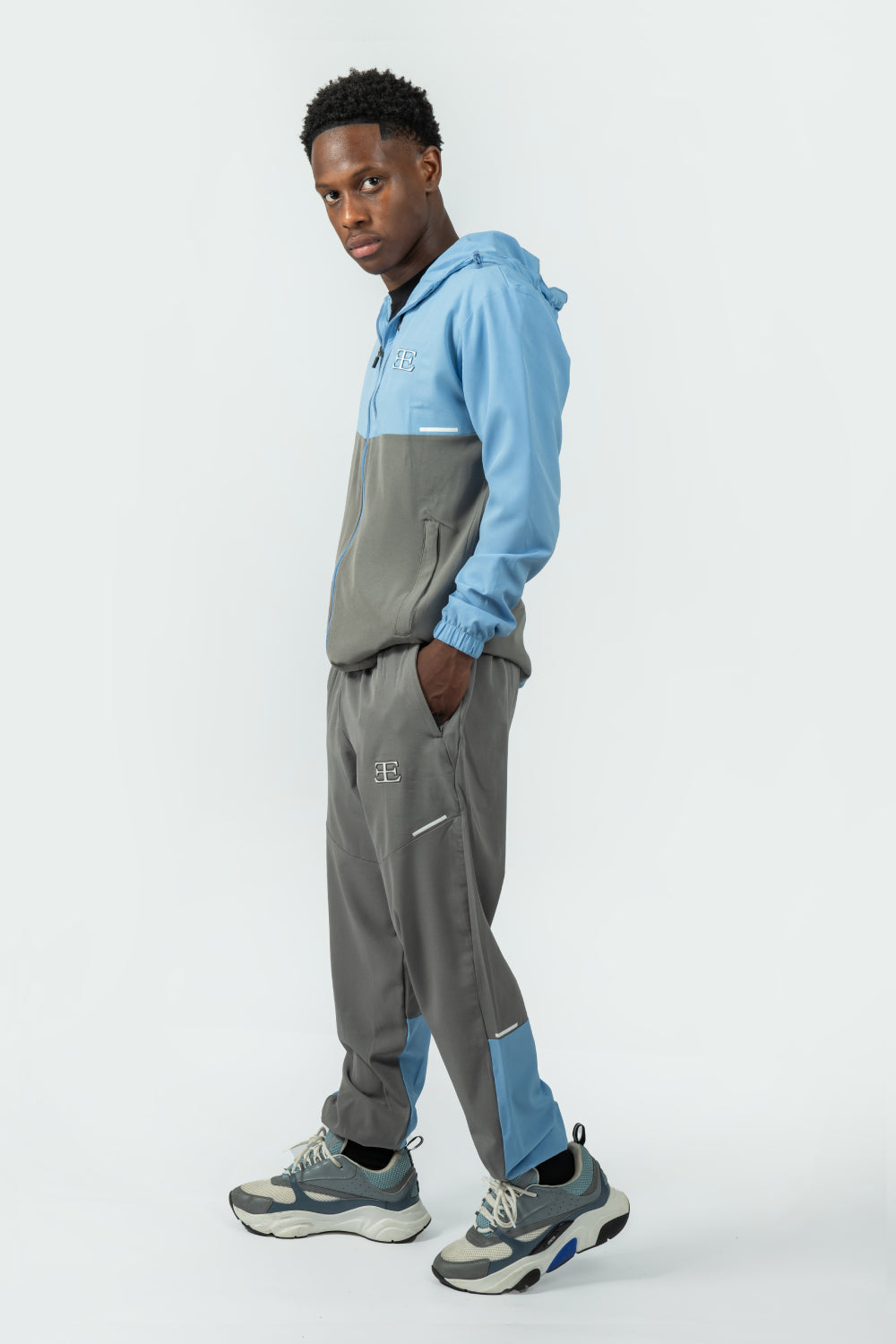 man wearing a grey and blue tracksuit on a white background