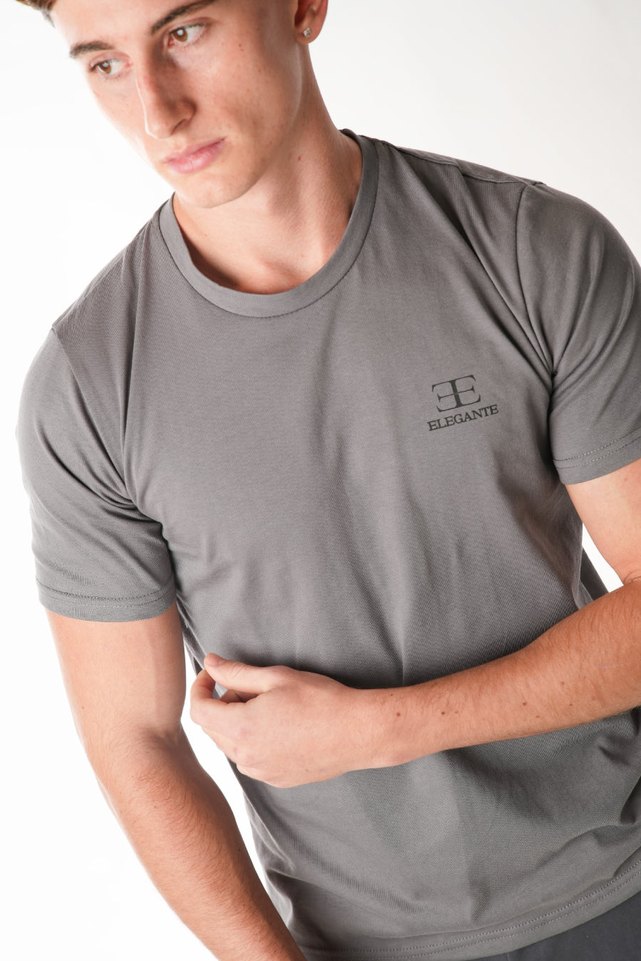 man wearing grey tshirt with elegante logo on chest on white background