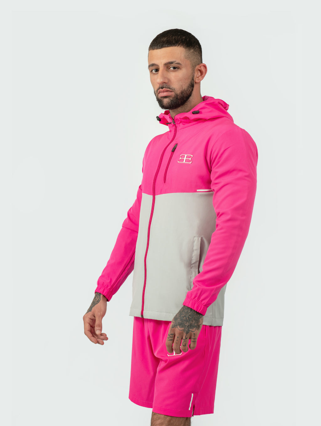 Man wearing a pink and gray tracksuit with a brand logo on a white background