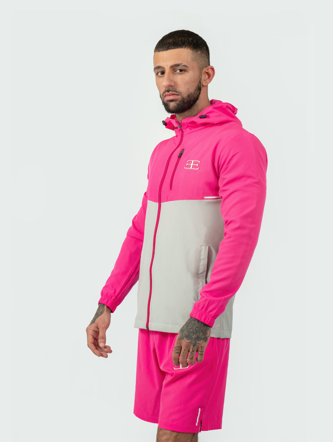 Man wearing a pink and gray tracksuit with a brand logo on a white background
