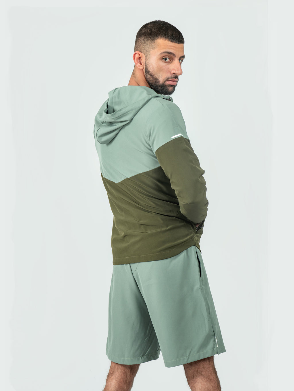 Man wearing a green and olive tracksuit on a white background