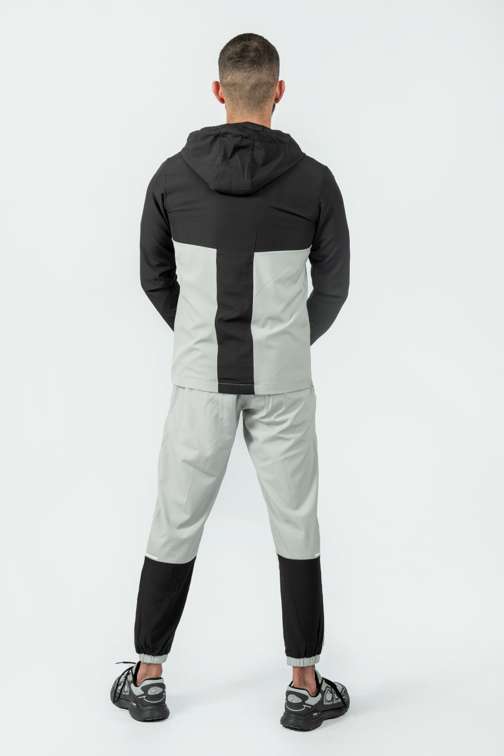Person wearing a black and gray tracksuit on a white background
