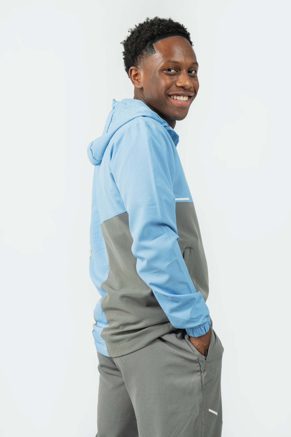 man wearing a light blue and grey jacket on a white background