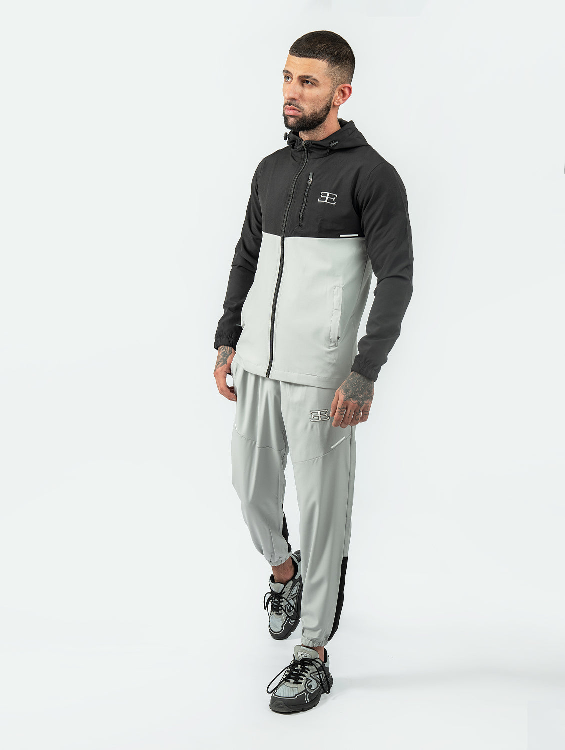 Man wearing a black and gray tracksuit on a white background
