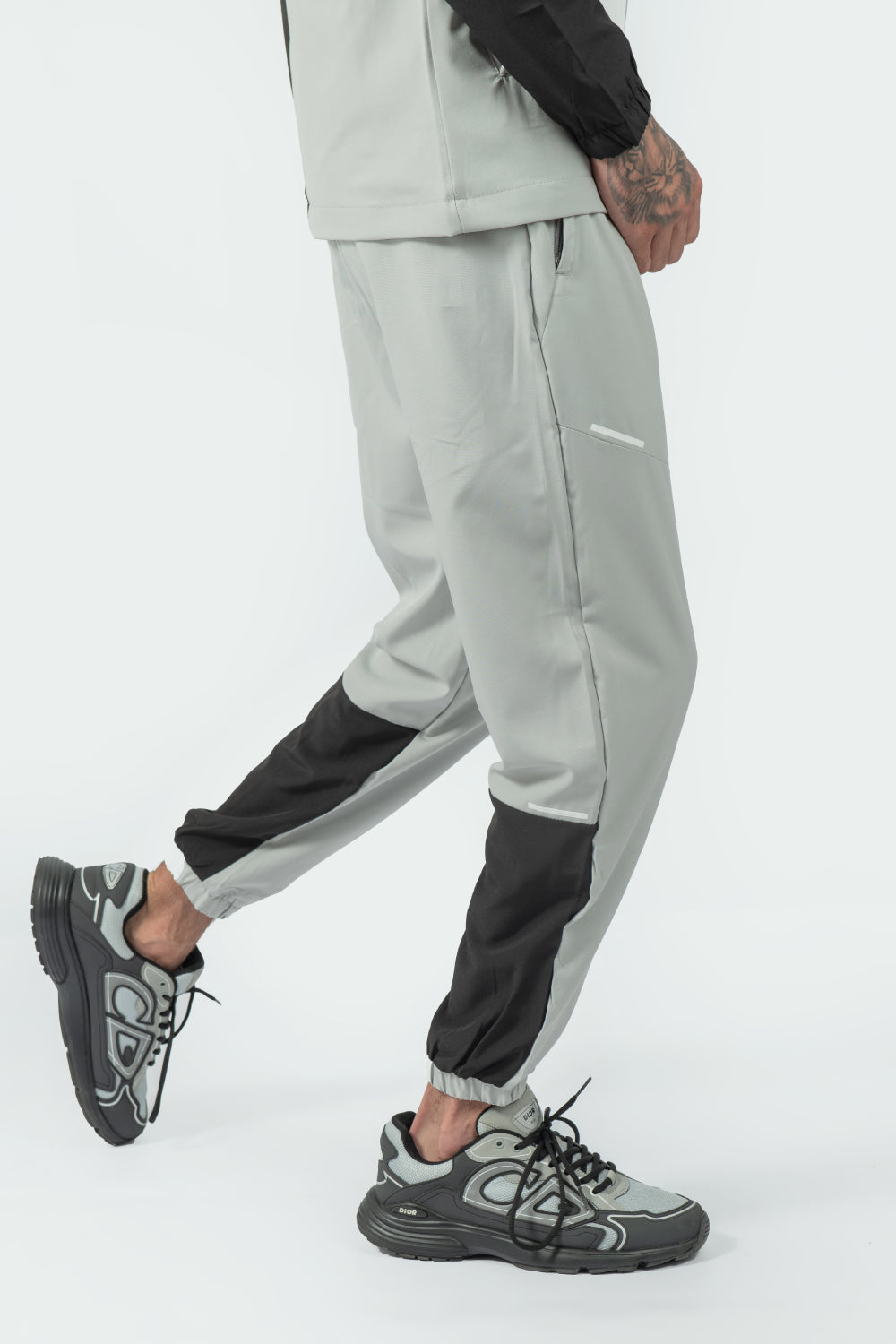 Person wearing gray jogger pants with black accents on a white background