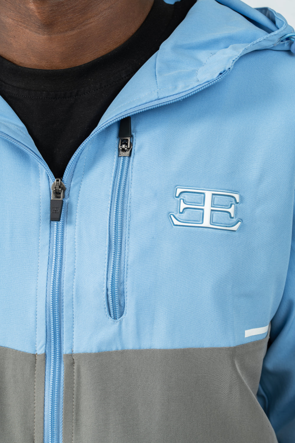 Close-up of a blue and grey jacket with a brand logo on the chest, zip pocket on chest