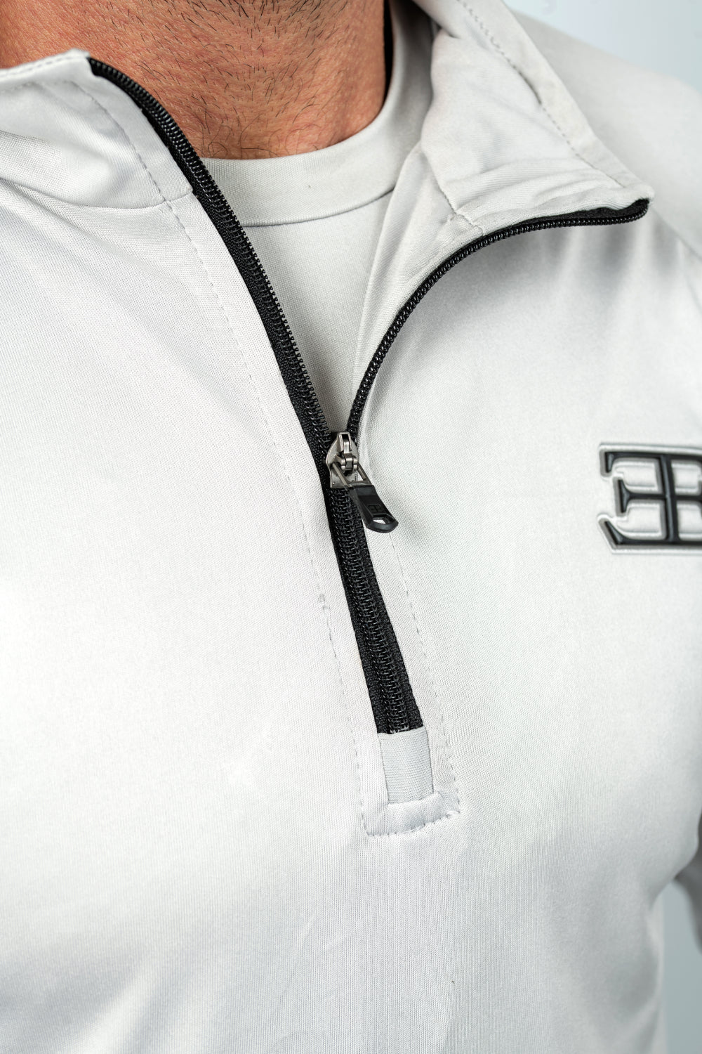White half-zip jacket with black zipper and logo on a white background